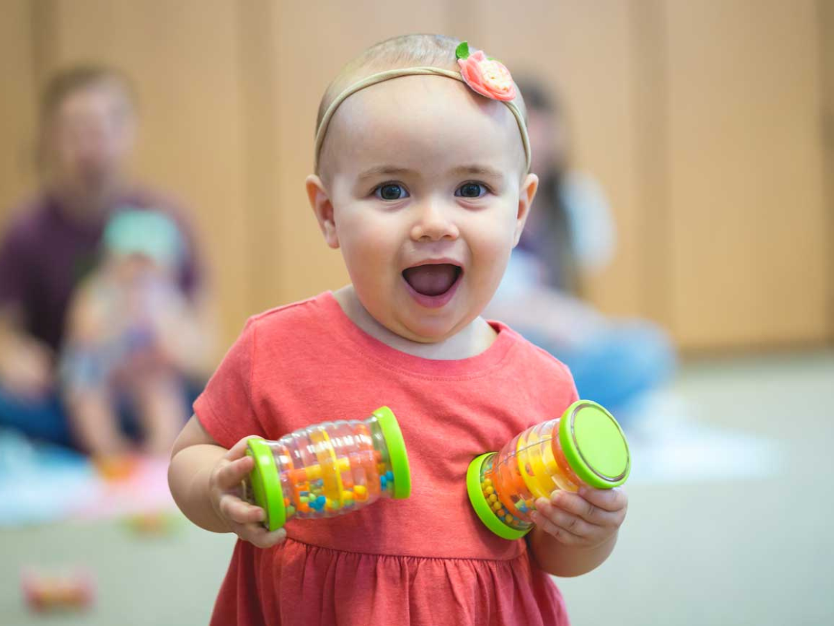 Toddler laughing with shaker eggs in a Kindermusik playdate class